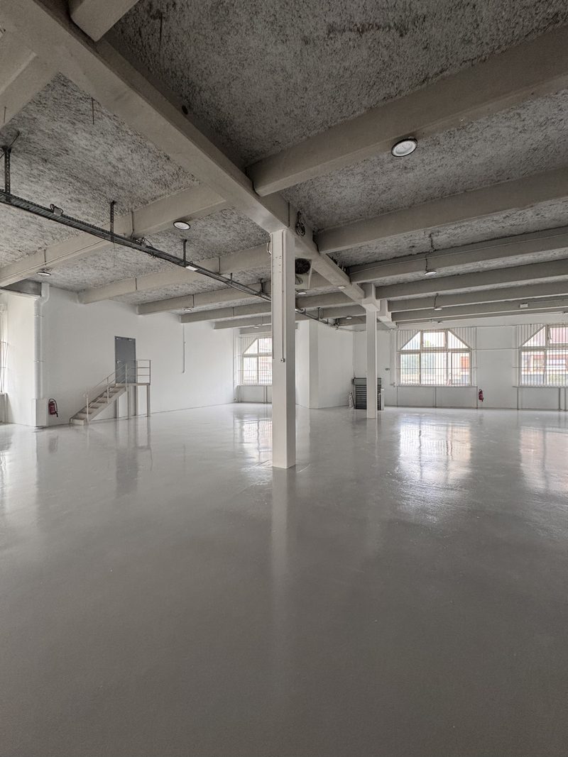 Local d'activité 1 200 m² — sol résiné gris, murs blancs, colonnes